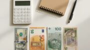 Зображення доларів США, євро, злотих і гривень на столі — порівняння валют для зберігання заощаджень.